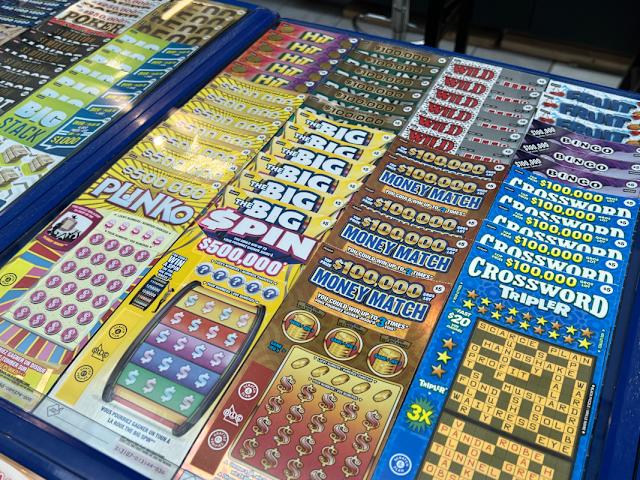 Lottery and scratch ticket terminal (18+). Table with lottery terminal, scratch tickets, and signage. For adults 18+ only.